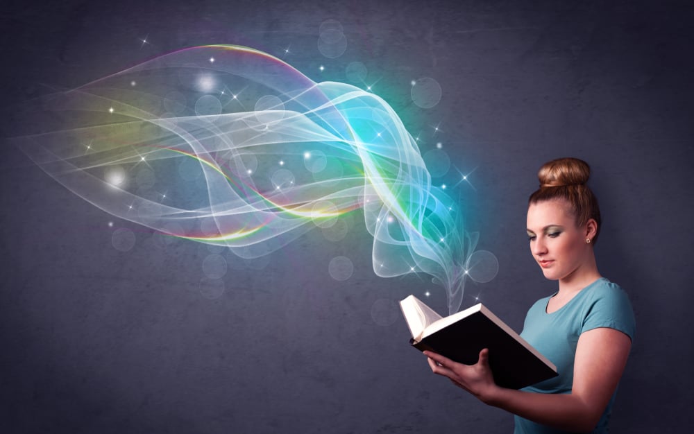 Casual young woman holding book with rainbow waves flying out of it