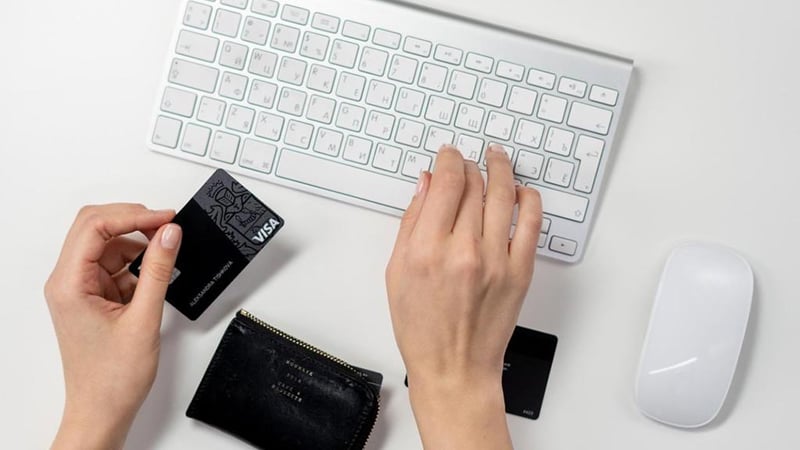 Woman typing at a keyboard with a credit card in hand.