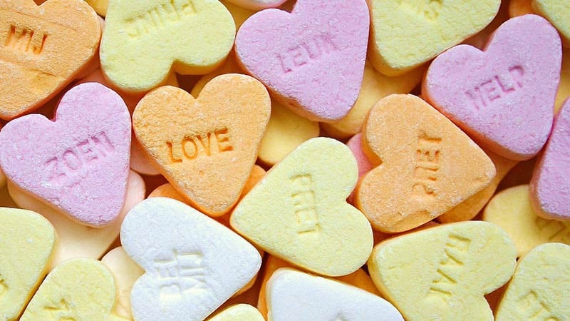 Heart shaped candy with words and names stamped into the surface.