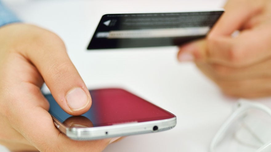 A man's hands holding his mobile phone and a creditcard.