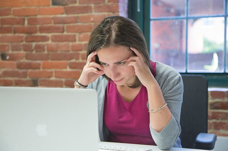 Youn woman sitting at a computer looking worried