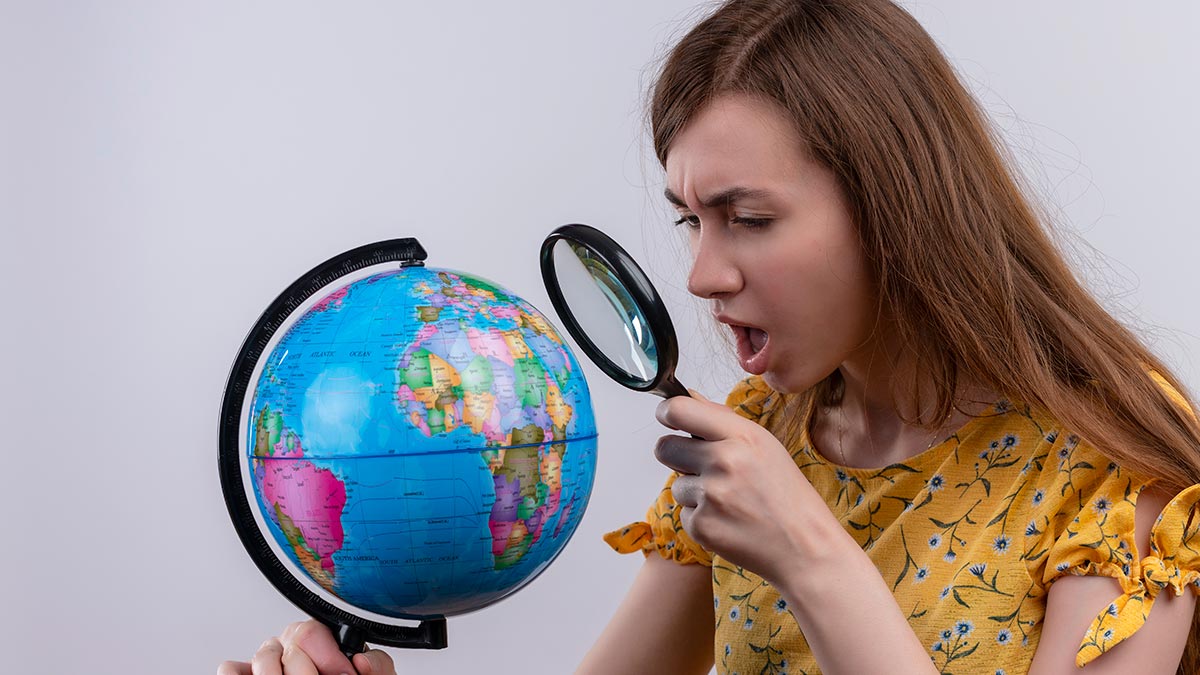 young-woman-holding-globe-looking-through-magnifier-glass